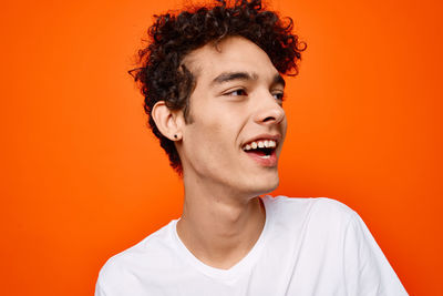 Smiling young man against orange background
