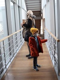 Rear view of women standing on railing