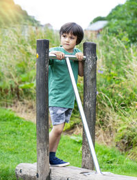 Full length of boy standing on wood against plants