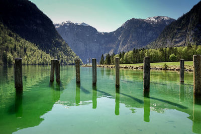 Wooden posts in lake against mountains