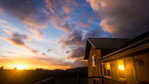 Silhouette houses against sky during sunset