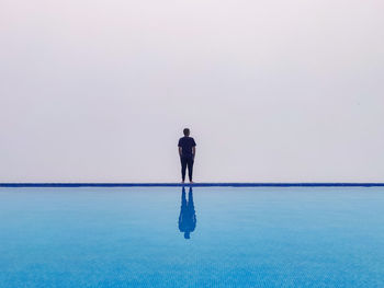 Rear view of man looking at sea against sky