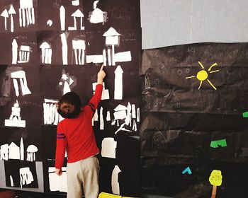 Full length portrait of boy standing against wall
