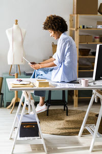 Businesswoman using digital tablet while sitting on desk at studio