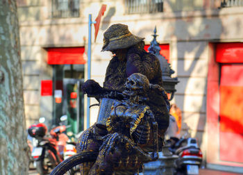 Statue of man with bicycle on street