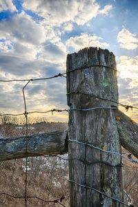 Close-up of wooden post against sky