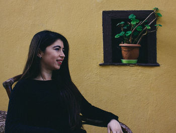 Portrait of young woman against wall with flower