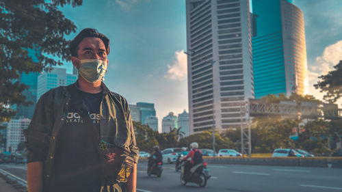 Man standing by modern buildings in city