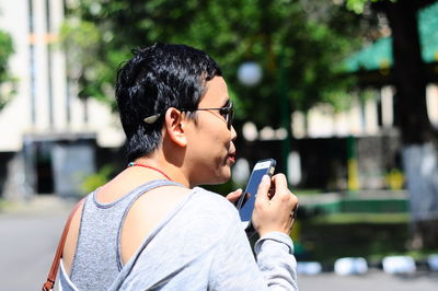 Rear view of man using mobile phone outdoors