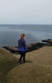 Rear view of woman standing on beach against sky