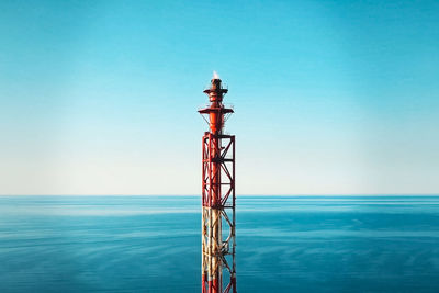 Tower against sea against clear blue sky