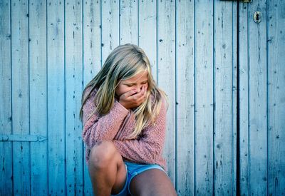 Portrait of a teenage girl sitting on wood