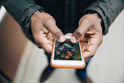 Midsection of man holding smart phone on table