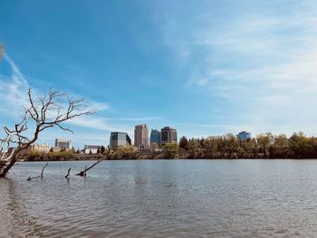 Buildings by river against sky in city