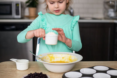 Little girl making dough in kitchen . small child cooking at home. kid making homemade muffins