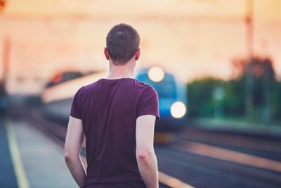 Rear view of man standing at railroad station