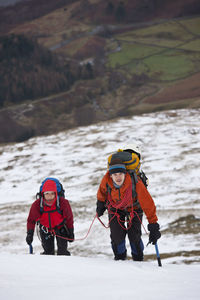 Couple hiking up helvellyn mountain in the winter