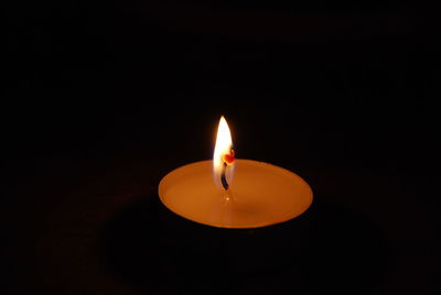 Close-up of burning candle against black background