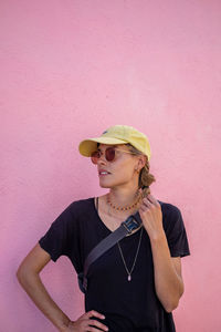 Side view of young woman standing against wall