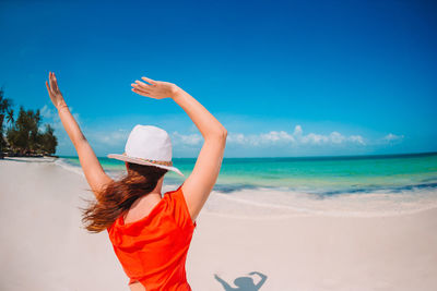 Rear view of woman at beach against sky