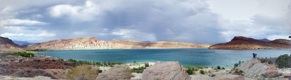 Panoramic view of sea by mountains against sky