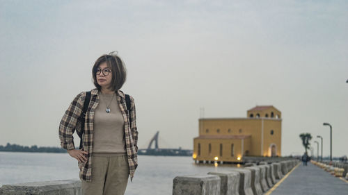 Young woman standing against sky