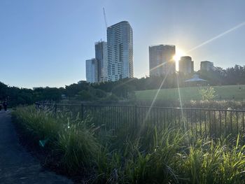 Modern buildings by river against clear sky