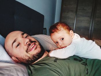 Portrait of man relaxing with baby boy on bed at home