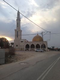 Road by building against sky during sunset in city