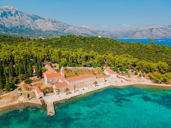 Monastery on an island in croatia surrounded by mountains and bright blue sea.