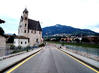 Road by buildings against sky in city