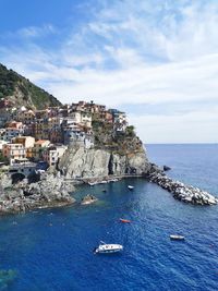 Sailboat in sea by townscape against sky