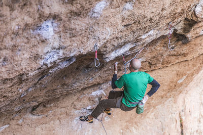 Climber hanging on rope on rough cliff