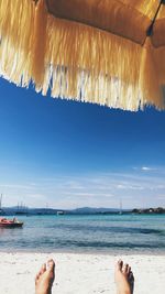 Low section of people on beach against sky