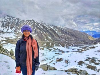 Portrait of smiling woman standing on snowcapped mountains during winter