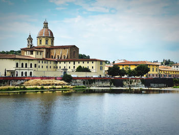 Buildings by river against sky