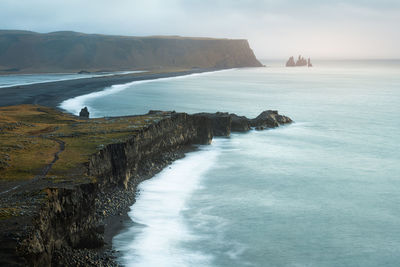 Dramatic sunrise at scenic cliff looking to reynisfjara black sand beach and reynisdrangar