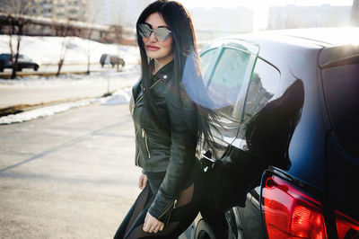 Portrait of fashionable woman standing by car
