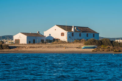 Houses by sea against clear blue sky