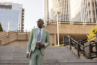 Mature businessman with laptop and coffee cup on steps