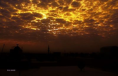 Silhouette of buildings against cloudy sky