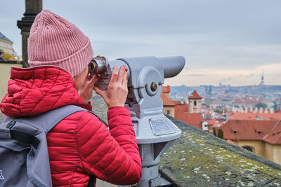 Rear view of man photographing through binoculars
