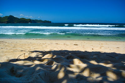 Scenic view of beach against clear blue sky