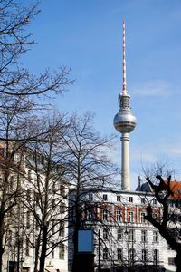 Low angle view of communications tower and buildings against sky