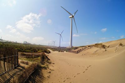 Wind turbines on land against sky