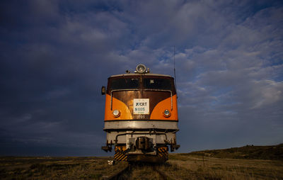 Train on railroad track amidst field against sky
