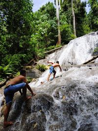 People relaxing on rock against trees