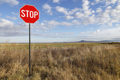 Road sign on field against sky