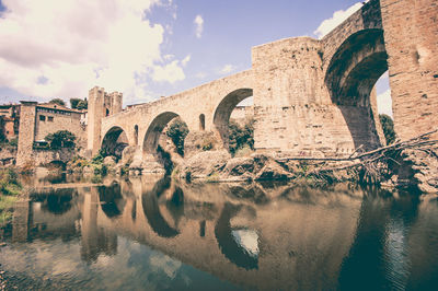 Arch bridge over river against sky