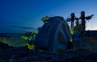 Bucket-wheel excavator at open-pit mine against sky at dusk